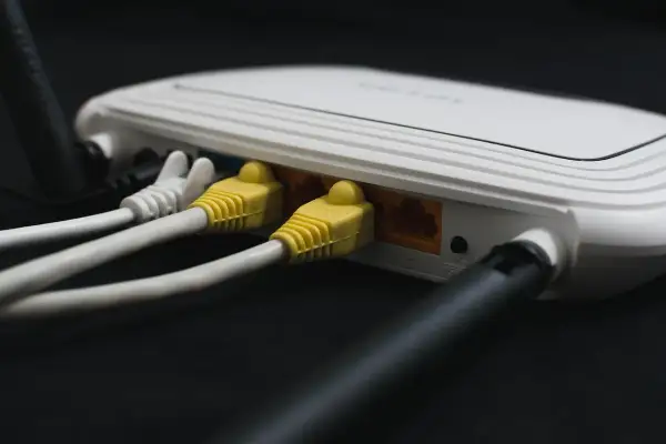 Router z podłączonymi żółtymi i białymi kablami sieciowymi. Ten kabel od internetu zapewnia połączenie.