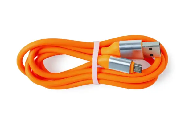 Pomarańczowy kabel USB z wtyczkami USB-A i micro USB. Czy silikon przewodzi prąd? Ten kabel pokazuje, że jego izolacja nie przewodzi.
