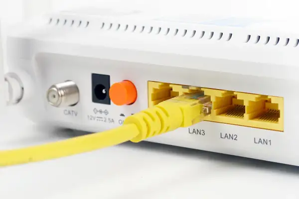 Żółty kabel sieciowy podłączony do portu LAN3 routera. Widoczne też złącze CATV i zasilania.