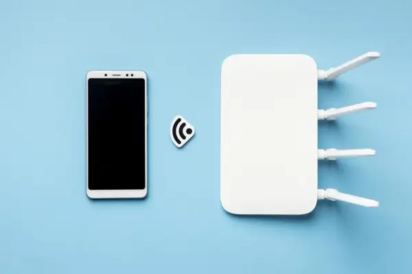Biały smartfon i router Wi-Fi obok symbolu połączenia. Dowiedz się, jak udostępnić internet z telefonu na telefon.