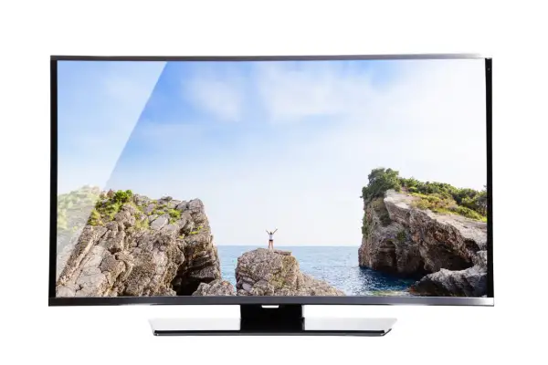 Na ekranie telewizora widok na morze, skały i osobę z rękami w górze. Brak obrazu w telewizorze, gdyby nie ten piękny krajobraz.